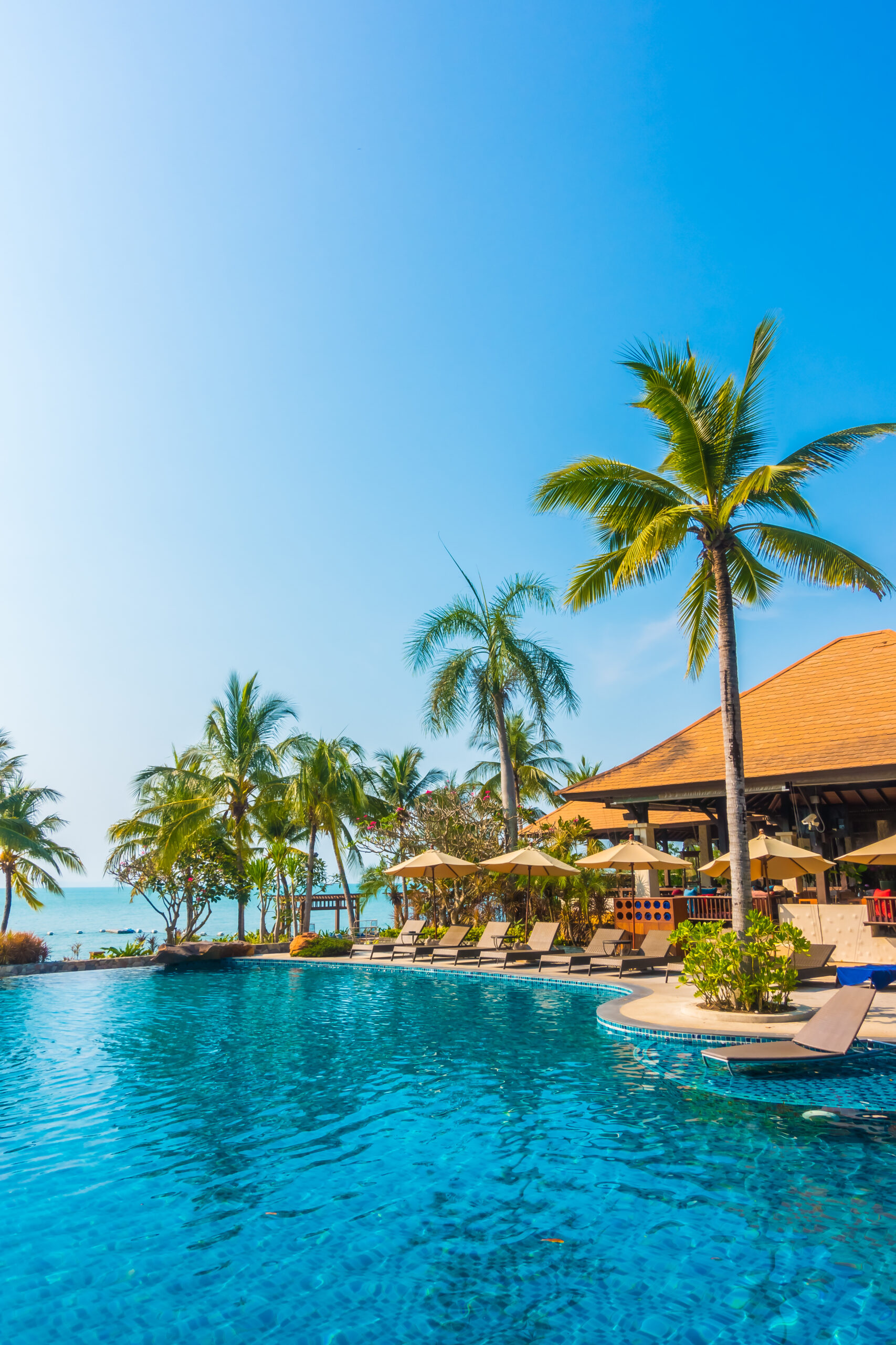 Beautiful luxury Swimming pool with palm tree and sea background in hotel pool resort - Boost up color Processing